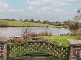 A view of a lake with greenery and a gate at Ty Llyn in Brynteg near Benllech