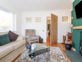 A living room with a sofa and armchair and decorative pictures at Wansfell View in Ambleside
