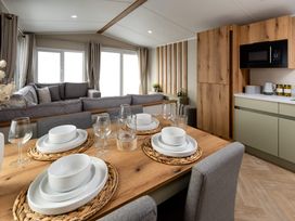 A dining area with a table set with dishes and a view of a living space at Ashberry 39 x 12 Three Bed- 2 Northwich