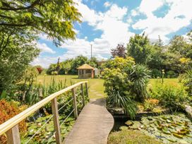 A garden with a bridge and gazebo at Pillars Barnstaple