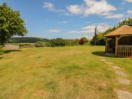 A garden with grass, a gazebo, and trees at Pillars in Barnstaple