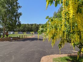 A view of a caravan site with yellow flowers and trees at Cedar Lodge 3 Bedrooms in Delamere