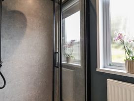 A shower area with glass panel and window at Cedar Lodge 3 Bedrooms in Delamere