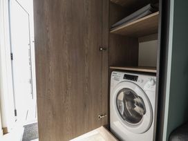 A laundry room with a washing machine and storage shelves at Cedar Lodge 3 Bedrooms Delamere
