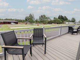 A deck with chairs overlooking a grassy area at Cedar Lodge 3 Bedrooms Delamere