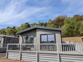 A cabin with large windows and a deck at No.11 - Cedar Lodge in Delamere
