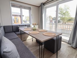 A dining room with a table and sofa at No.11 - Cedar Lodge in Delamere