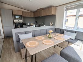 A dining area with a table and kitchen in No.11 - Cedar Lodge Delamere
