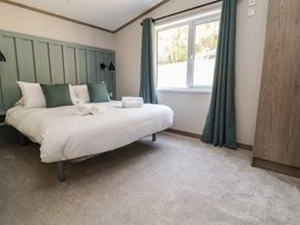 A bedroom with a bed and wardrobe at No.11 - Cedar Lodge Delamere