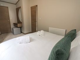 A bedroom with a bed and towels at No.11 - Cedar Lodge in Delamere