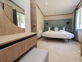 A bedroom with a bed and dresser at No.11 - Cedar Lodge in Delamere