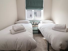 A bedroom with two single beds and a nightstand at No.11 - Cedar Lodge in Delamere
