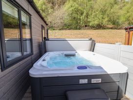 A hot tub outside with trees and a wooden wall at No.11 - Cedar Lodge in Delamere