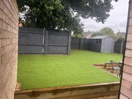 A garden with artificial grass, a shed, and a fenced area at 43 Goose Green Road in King's Lynn