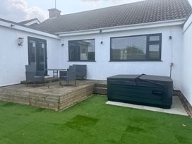 An outdoor area with a table and chairs next to a hot tub at 15 Lamsey Lane King's Lynn