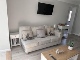 A living room with a sofa and side tables at 22 Sandringham Drive in King's Lynn