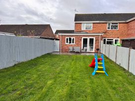 A garden with a slide and patio seating at 22 Sandringham Drive King's Lynn