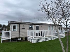 A mobile home with a deck and grass at 55 Cambrian Park