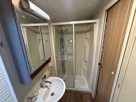 A bathroom with a shower, sink, mirror, and door at 55 Cambrian Park