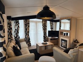 A living room with sofa, coffee table and television at Hafan Y Mor Haven Pwllheli