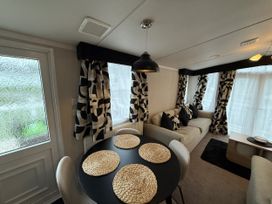 A living room with a sofa and dining table at Hafan Y Mor Haven Pwllheli