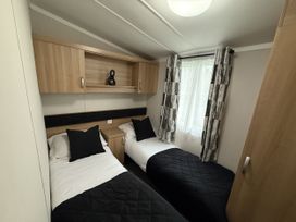 A bedroom with twin beds and a window at Hafan Y Mor Haven Pwllheli