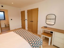 A bedroom with a bed, table, and mirror at 1 Dairy Fields Longframlington
