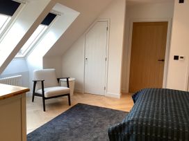 A bedroom with an armchair and a bed at The Barn in Longframlington