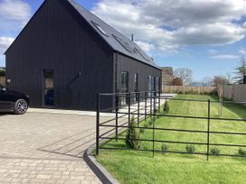 A house with a car parked in front and a garden at The Barn in Longframlington