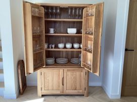 A wooden cupboard with glassware and dishes at The Barn in Longframlington