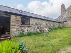 A garden with a table and chairs outside at Little Tregarrick in Helston