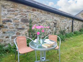 A garden with a table and chairs arranged with flowers and a book at Little Tregarrick in Helston