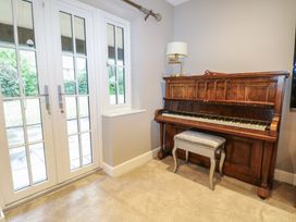 A music room with a piano and windows at Woodlands house in Ringwood