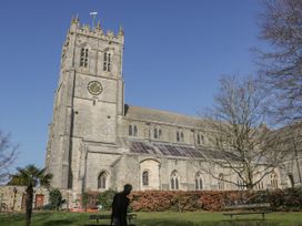 A church with a tower and clock surrounded by trees and bushes at Woodlands house in Ringwood