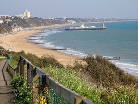 A beach with a pier and pathway at Woodlands House in Ringwood