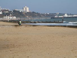 A beach with a person walking near the water at Woodlands House in Ringwood