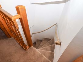 A staircase with a wooden handrail and carpet at Park Cottage in Kingsbridge