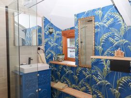 A bathroom with a blue wallpaper and glass shower at Park Cottage in Kingsbridge