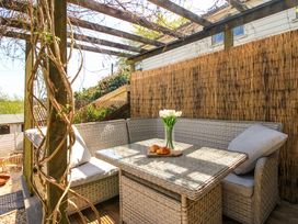 An outdoor seating area with wicker furniture and a vase of flowers at Park Cottage in Kingston, Kingsbridge