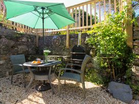A garden with a table, chairs, and grill at Park Cottage in Kingston, Kingsbridge