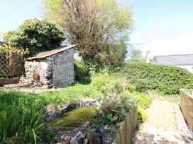 A garden with a stone shed and pond at Park Cottage in Kingston, Kingsbridge