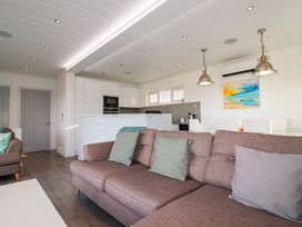 A living room with a sofa and kitchen area at 114 - The Residance in Redruth