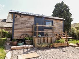 An exterior view of a wooden hut with steps and garden features at Dunfell Shepherd's Hut in Appleby-In-Westmorland