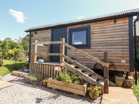 An outdoor view of a wooden structure with steps and garden features at Dunfell Shepherd's Hut Appleby-In-Westmorland