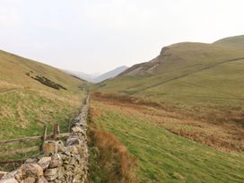 A valley with a stone wall and hills at Dunfell Shepherd's Hut in Appleby-In-Westmorland