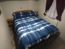 A bedroom with a bed and nightstand at Whispering Meadows - 104 Great Yarmouth