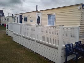 A mobile home with a deck and railing at Whispering Meadows - 104 Great Yarmouth