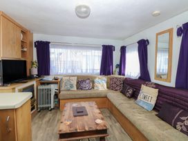 A living room with a sofa and coffee table at Whispering Meadows - 104 in Hemsby
