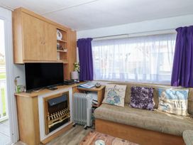 A living room with a television and a sofa at Whispering Meadows - 104 Hemsby