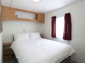 A bedroom with a bed and shelf at Whispering Meadows - 104 Hemsby